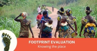 People walking and riding motorbikes along a dirt road surrounded by lush vegetation in Africa 