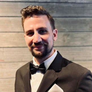 Person in a suit and bowtie, smiling at the camera