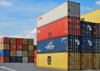 Several colourful shipping containers stacked up at a port