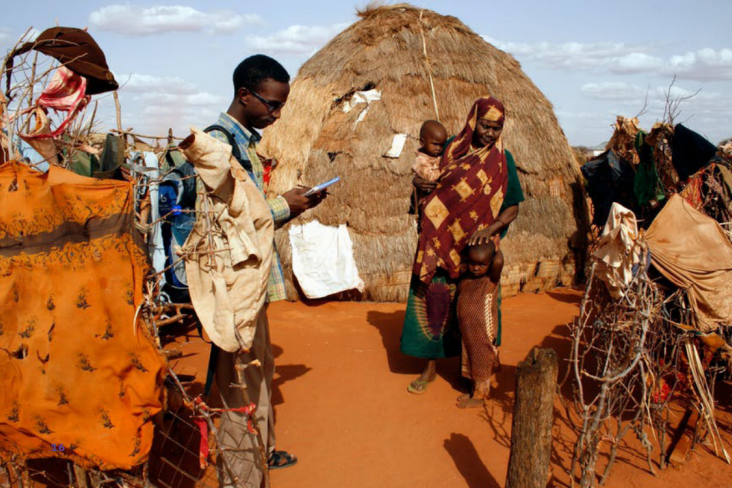 A person talks with a family outdoors in Kenya